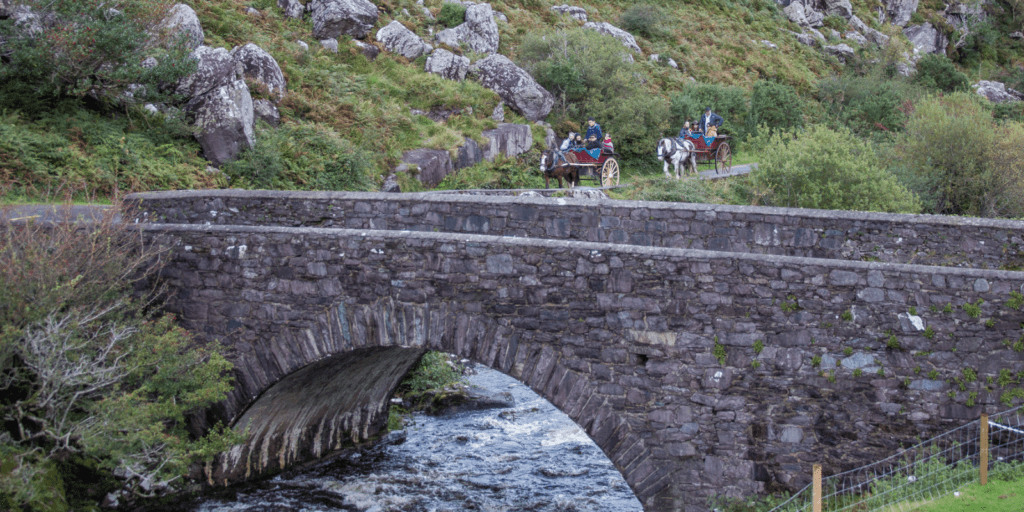 A group of people riding horses over a bridge