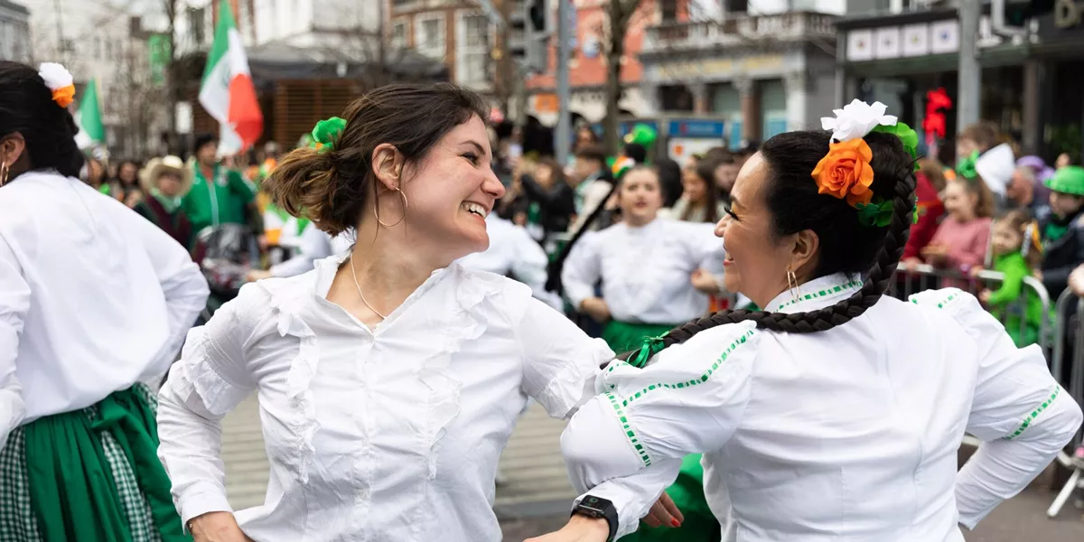 Two women in green skirts dancing and celebrating St Patrick's Day in Dublin