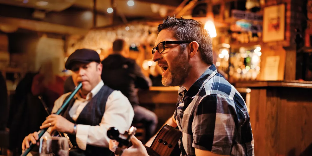 Two men playing the guitar and flute in a pub