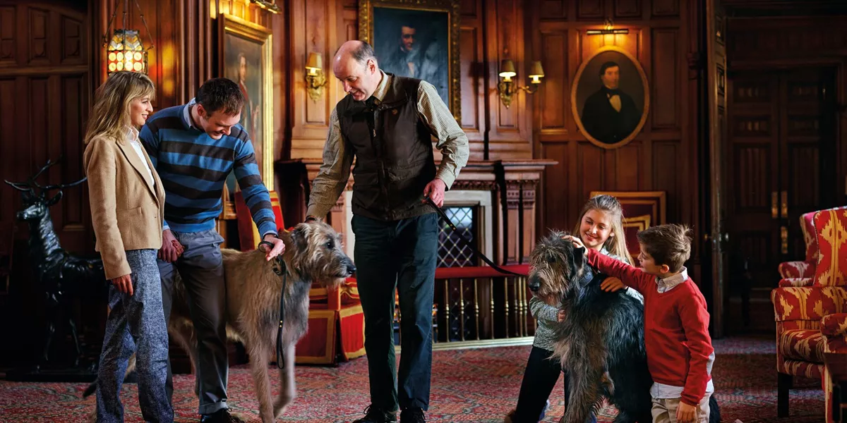 Family with two large wolf hounds in grand hallway of old house