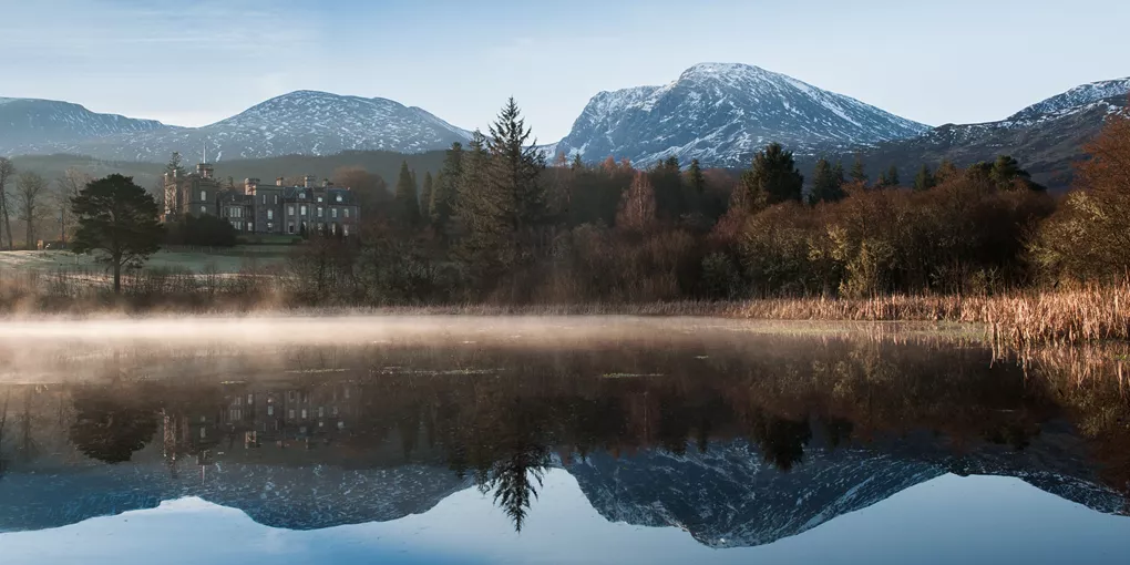 Inverlochy Castle in  Scotland's Highlands surrounded by hills and lake 