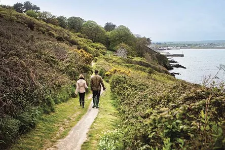 Couple walking along a country path next to the sea
