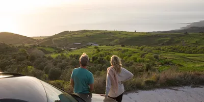 Couple pause at the roadside and looking upon sea valley in Ireland