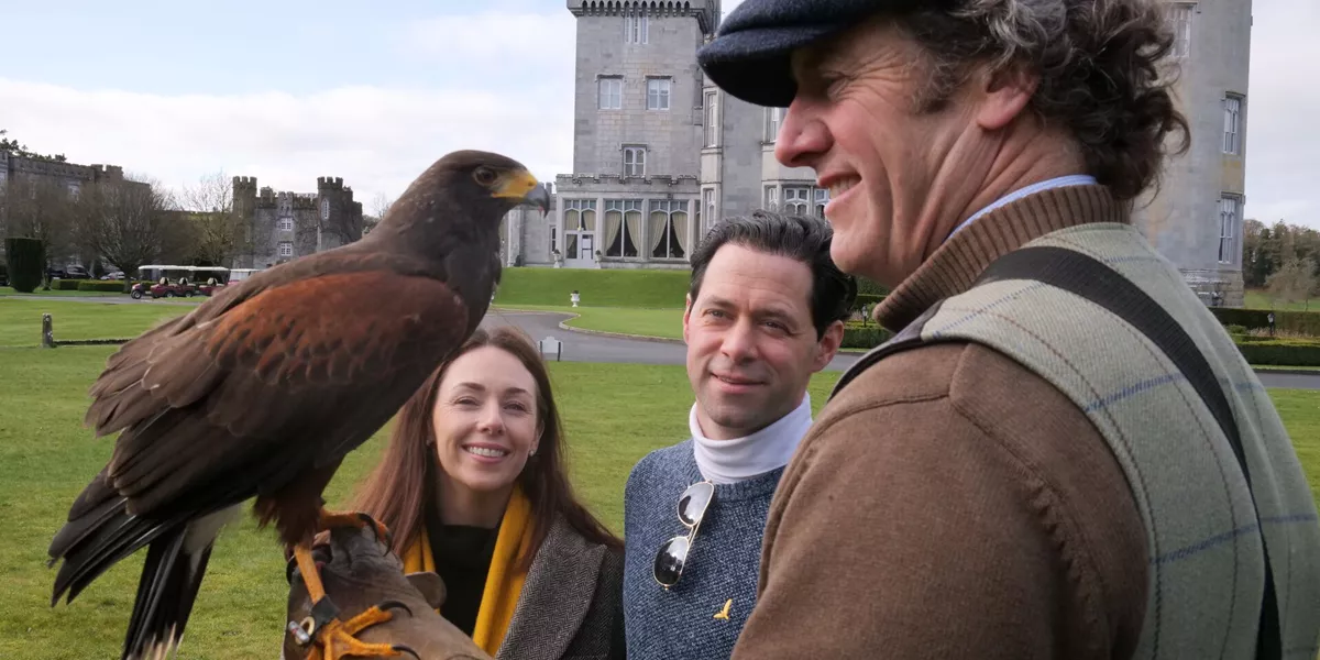 Three people with a falcon in front of Dromoland Castle in Ireland